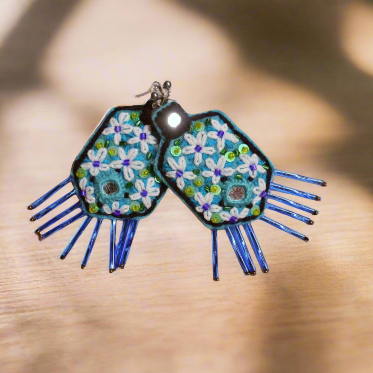 Unique hand-embroidered floral earrings with soothing blue and green tones, designed for nature lovers