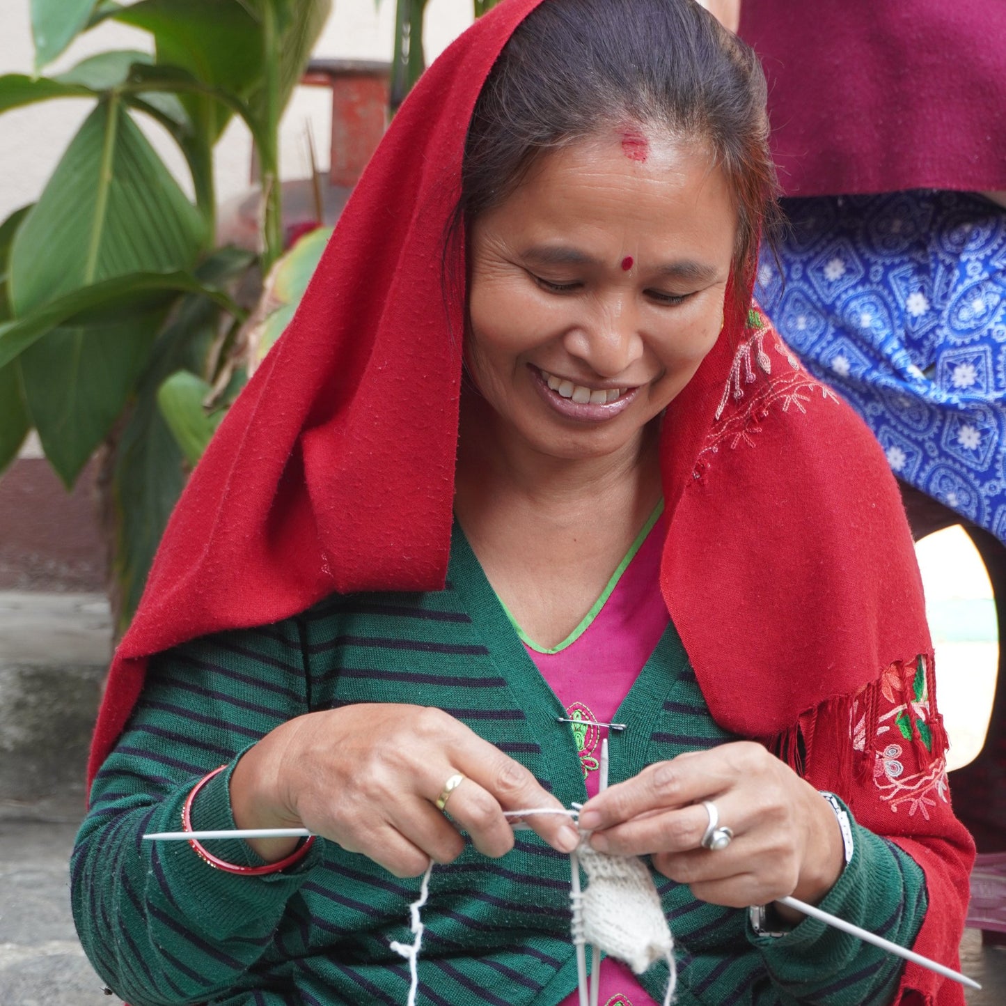 a Nepali artisan supported by Gry & Sif’s fair trade practices, crafting a handmade wool mouse ornament with a red heart for unique holiday decor and thoughtful gifts