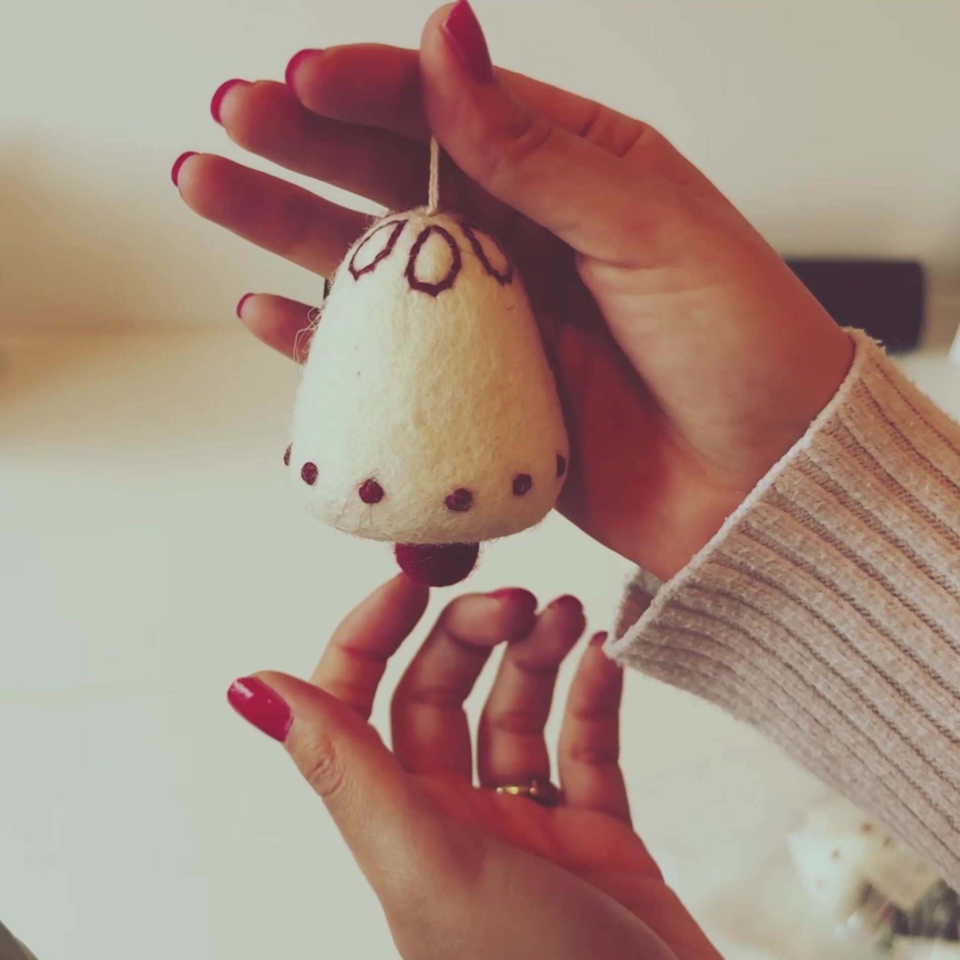 Video showcasing a handmade wool bell ornament by Gry & Sif, perfect for fair trade Christmas decor and as a thoughtful gift, crafted in Nepal with a white and red design